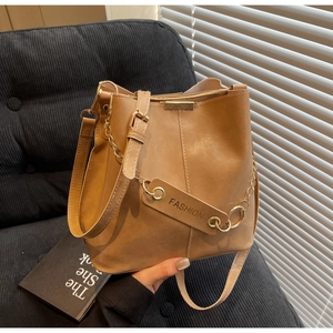 Close-up of caramel leather bucket bag with gold chain and fashion tag detail