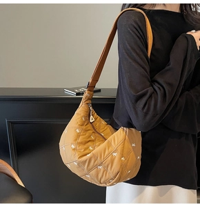 Detail of tan quilted crossbody bag with white bow pattern and wide shoulder strap