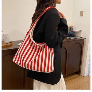 Detailed side view of large red and white striped tote bag worn by model in casual setting