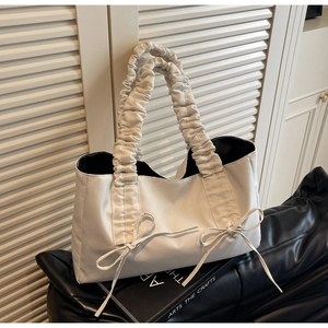 Detail of cream white tote bag featuring pleated cloud handle and bow knot ribbons