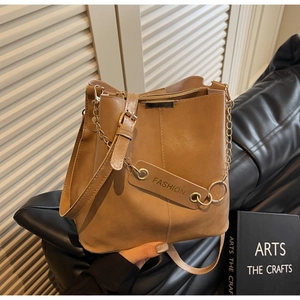 Detail of khaki leather bucket bag with gold chain strap and fashion tag in hand