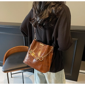 Detail view of brown vintage bucket bag with golden chain and FASHION decorative strap