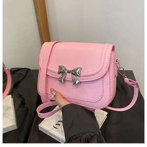 Détail du petit sac bandoulière en similicuir rose avec nœud métallique argenté