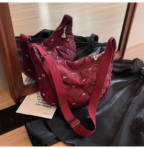 Macro detail of wine red quilted bag with white bow embroidery and mirror reflection