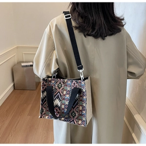 Ethnic pattern woven tote bag with adjustable strap worn by a model in a modern interior
