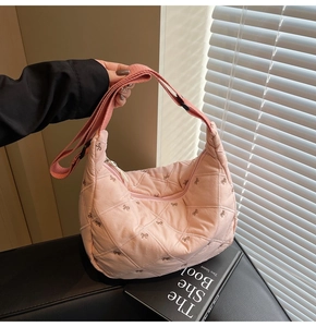 Detailed macro view of pink quilted bow embroidery texture on a soft shoulder bag