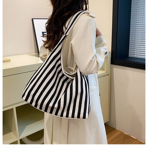 Lifestyle view of a large black and white striped canvas tote bag worn over the shoulder