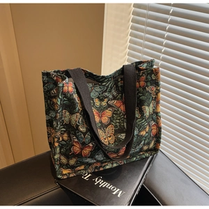 Close-up of vintage butterfly jacquard tote bag with black woven handles and retro patterns