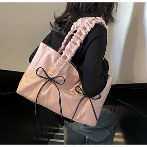 Detailed back view of pink tote bag featuring black bow accents and pleated shoulder straps