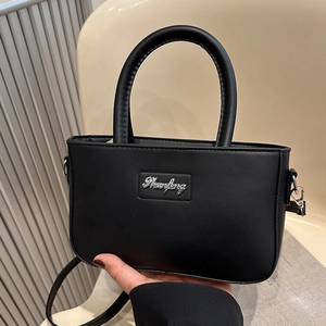 Minimalist black matte leather crossbody bag with silver metal branding and round handle