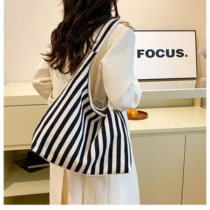 Fashionable black and white striped canvas tote bag worn by a model in a minimalist setting