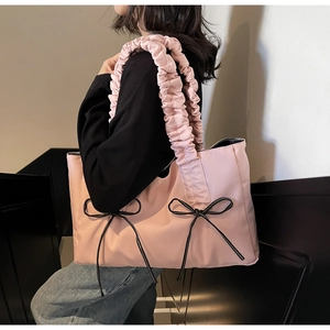 Pink nylon tote bag with pleated cloud handle and decorative black bows on a soft background