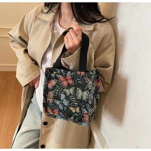 Detail of colorful butterfly jacquard pattern on a large black tote bag with woven handles