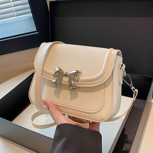 Sac bandoulière chic blanc crème avec nœud argenté sur une boîte cadeau