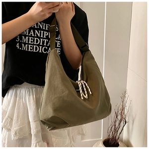 Dettaglio della grande borsa in tela verde oliva con corda intrecciata ed etichetta fashion