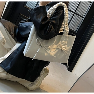 Detail of cream tote bag featuring ruffled handles and long bow ties in daily use