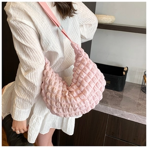 Detail shot of pink bubble fabric texture on a soft crescent-shaped crossbody bag