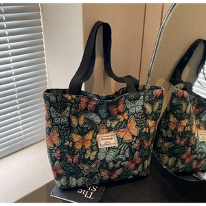 Detail of floral tapestry tote bag with colorful butterfly prints and black fabric straps