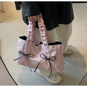 Close-up of light pink tote bag with black bow details and pleated handle design