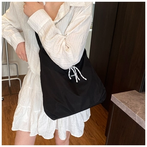 Dettaglio della borsa tote in tela nera con coulisse intrecciata e etichetta di moda