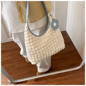 Détail du sac cabas à texture gaufrée avec bandoulière bleue et breloque fleur