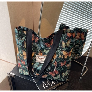 Detailed close-up of butterfly print canvas tote bag with black strap on display