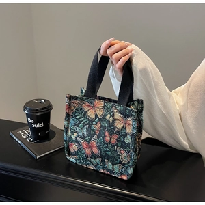 Detail of colorful butterfly knit tote bag with black woven handles and retro style
