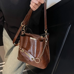 Vintage brown leather bucket bag with gold chain and fashion strap shown on model