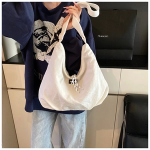 Dettaglio borsa a tracolla in tela bianca con cinturino regolabile ed etichetta moda