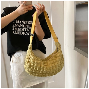 Close-up of yellow hobo bag with bubble texture and adjustable shoulder strap worn by model
