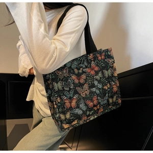 Detail of a large tote bag featuring colorful butterfly and flower prints on dark fabric