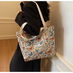 Detail view of large canvas tote bag with vintage floral and butterfly pattern on shoulder