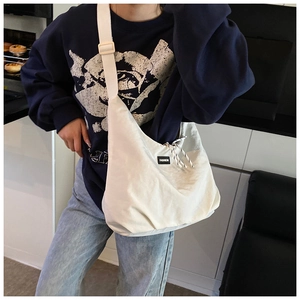 Dettaglio della borsa a tracolla in tela bianco sporco con etichetta moda e coulisse