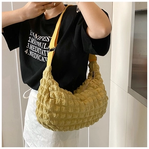 Detail of yellow textured puff crossbody bag with adjustable strap on female model