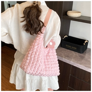 Détail du sac cabas rose à texture gaufrée avec breloque fleur porté par un mannequin