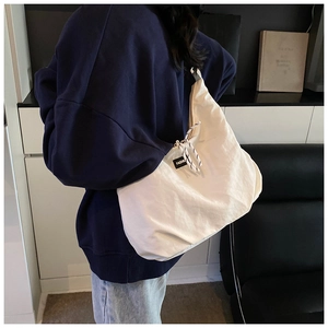 Dettaglio della borsa a tracolla in tela off-white con etichetta fashion e coulisse
