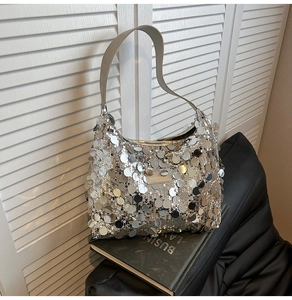 Detailed close-up of large silver sequins on a hobo bag with a metallic brand logo