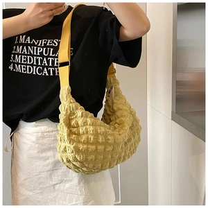 Detail of yellow crescent puff bag showing popcorn texture and wide adjustable strap
