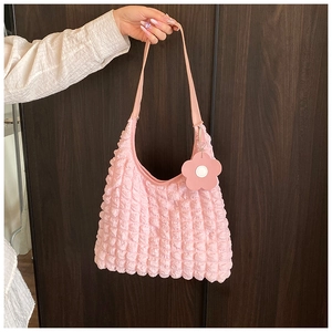 Détail du sac cabas rose à texture gaufrée avec un pendentif floral décoratif
