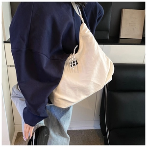 Dettaglio della borsa tote in tela bianca con etichetta fashion su sedia in pelle nera