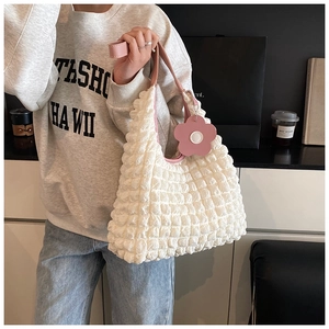 Détail du sac fourre-tout gaufré crème avec bandoulière en cuir rose et breloque