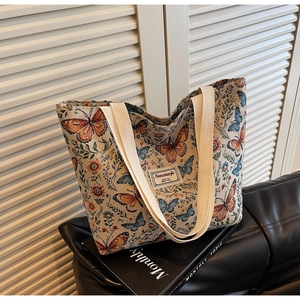 Detail of floral jacquard tote bag featuring orange butterfly patterns and cream handles