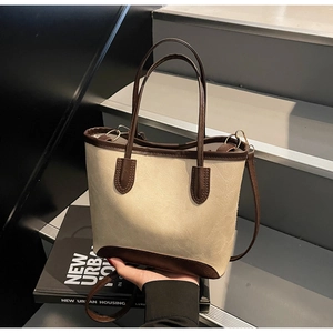 Detail of two-tone cream and brown tote bag with adjustable straps and gold buckle