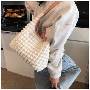 Détail du cabas blanc à texture gaufrée avec bandoulière rose et breloque fleurie
