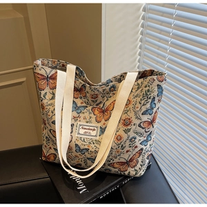 Detail of floral tapestry tote bag with butterfly patterns and woven handle