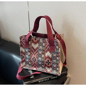 Detail of bohemian woven tote bag with red handles and ethnic geometric patterns