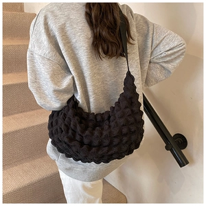 Close-up of black bubble textured crossbody bag with thick nylon shoulder strap