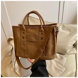 Detail of khaki canvas tote bag with black rivets and adjustable shoulder strap
