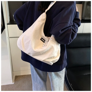 Dettaglio della grande borsa hobo in tela bianca con tracolla annodata e logo FASHION