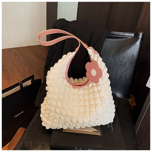Détail du sac fourre-tout blanc texturé avec bandoulière rose et breloque fleurie décorative